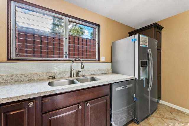 kitchen with sink, decorative backsplash, light tile patterned floors, appliances with stainless steel finishes, and dark brown cabinets