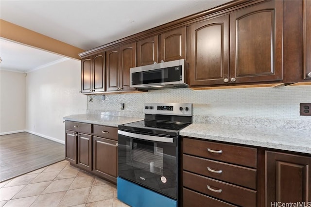 kitchen featuring light stone countertops, ornamental molding, dark brown cabinets, light tile patterned flooring, and stainless steel appliances