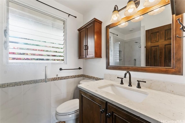 bathroom featuring vanity, a shower with shower door, tile walls, and toilet