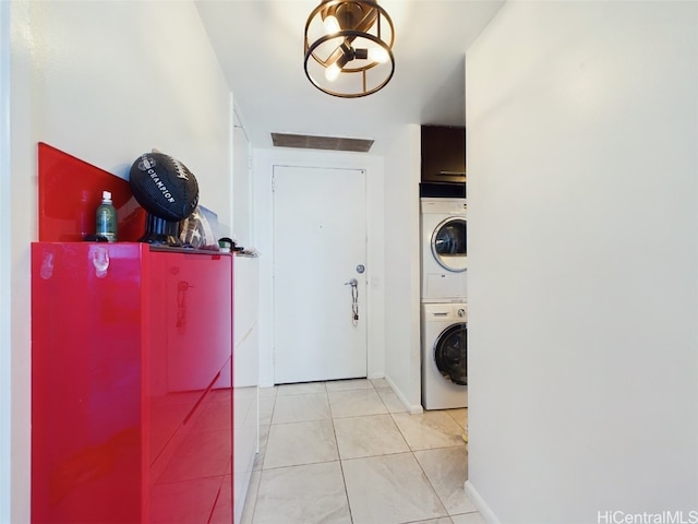 laundry room featuring stacked washer / dryer and light tile patterned floors