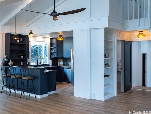 kitchen featuring a breakfast bar area, stainless steel refrigerator, beamed ceiling, and dark hardwood / wood-style floors