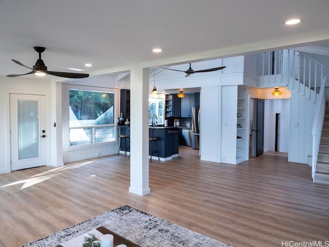 unfurnished living room featuring wood-type flooring, ceiling fan, and sink