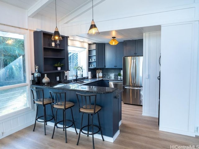 kitchen with stainless steel refrigerator, sink, hanging light fixtures, kitchen peninsula, and a kitchen bar