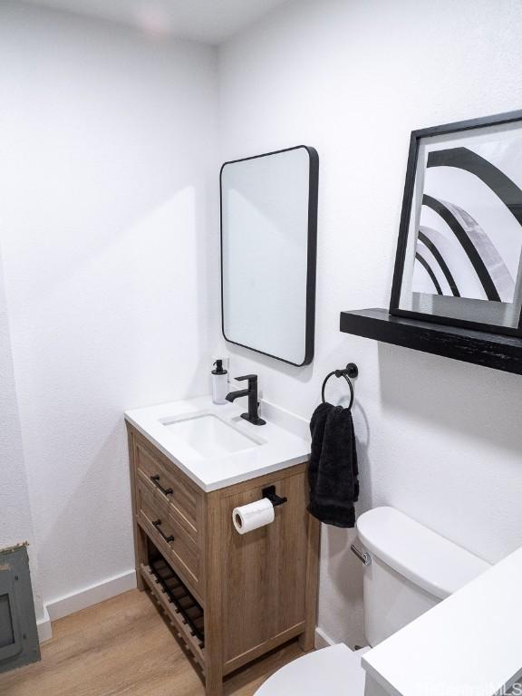 bathroom with hardwood / wood-style flooring, vanity, and toilet