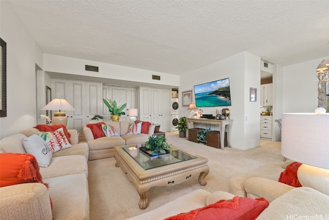 living room featuring a textured ceiling, light colored carpet, and stacked washer and clothes dryer