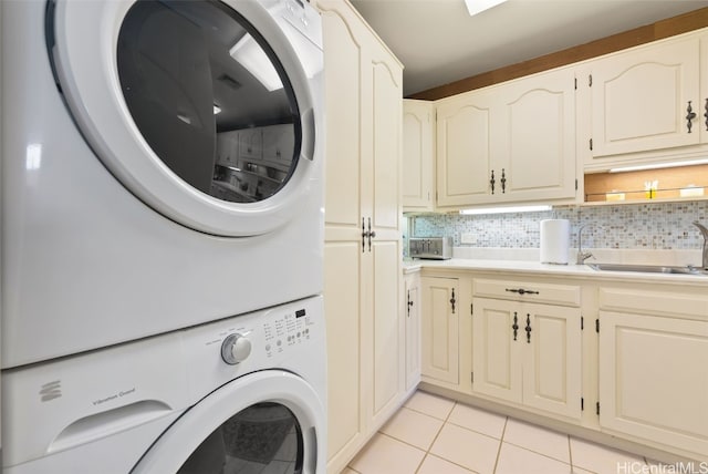 laundry room with stacked washer / dryer, sink, light tile patterned floors, and cabinets