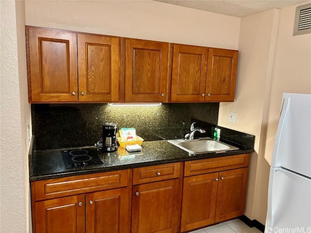 kitchen featuring light tile patterned floors, white refrigerator, tasteful backsplash, and sink