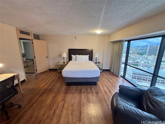 bedroom featuring wood-type flooring, a textured ceiling, and access to outside