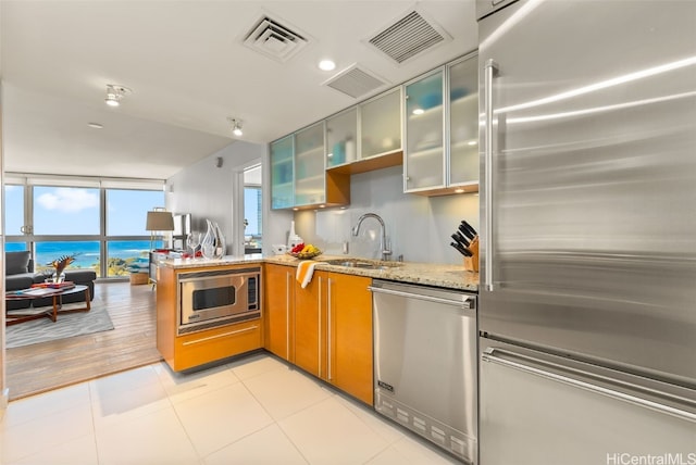 kitchen featuring sink, light stone countertops, light hardwood / wood-style floors, kitchen peninsula, and stainless steel appliances