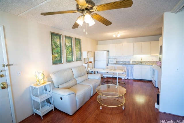 living room featuring a textured ceiling, dark hardwood / wood-style flooring, ceiling fan, and sink