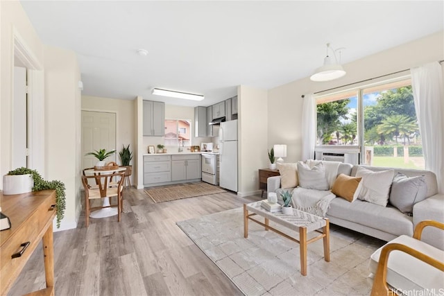 living room with sink, cooling unit, and light hardwood / wood-style floors