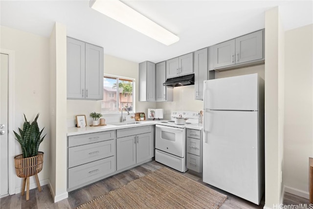 kitchen with white appliances, hardwood / wood-style flooring, gray cabinetry, and sink