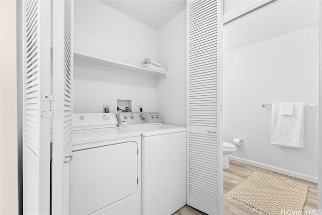 laundry room with washer and clothes dryer and light wood-type flooring