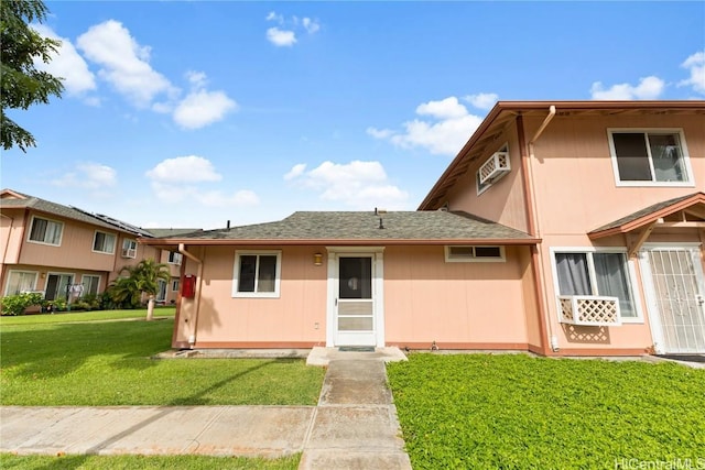 view of front of house with a front yard and a wall mounted air conditioner