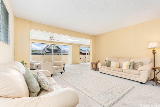 carpeted living room with ceiling fan and a textured ceiling