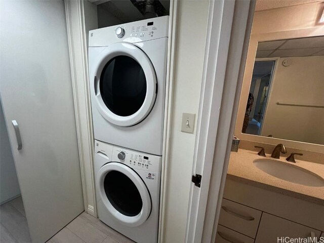 laundry room with light tile patterned floors, stacked washing maching and dryer, and sink