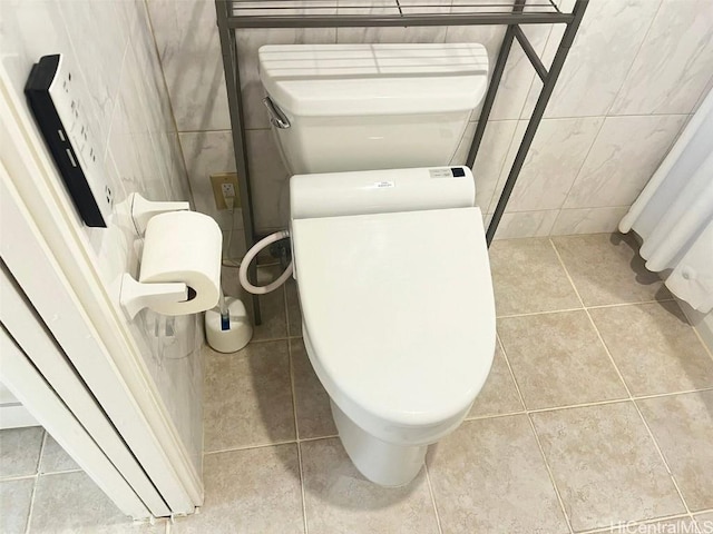 bathroom with toilet, tile walls, and tile patterned floors