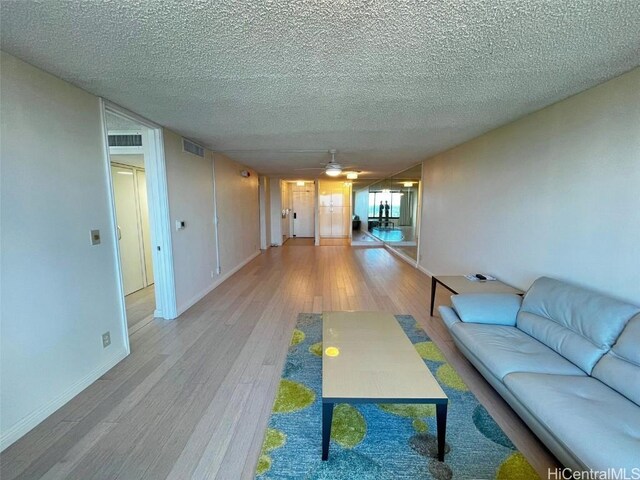 living room with hardwood / wood-style flooring, ceiling fan, and a textured ceiling