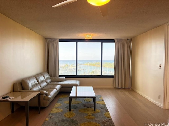 living area featuring light wood-type flooring, a water view, and baseboards