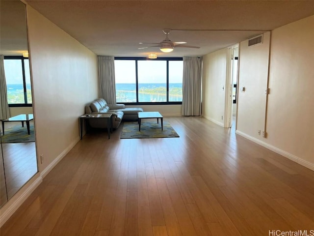 unfurnished room with baseboards, ceiling fan, visible vents, and wood finished floors