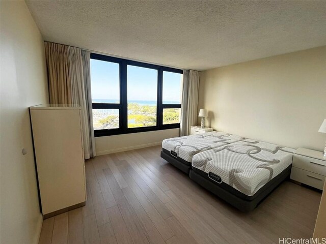 bedroom with light wood-type flooring and a textured ceiling