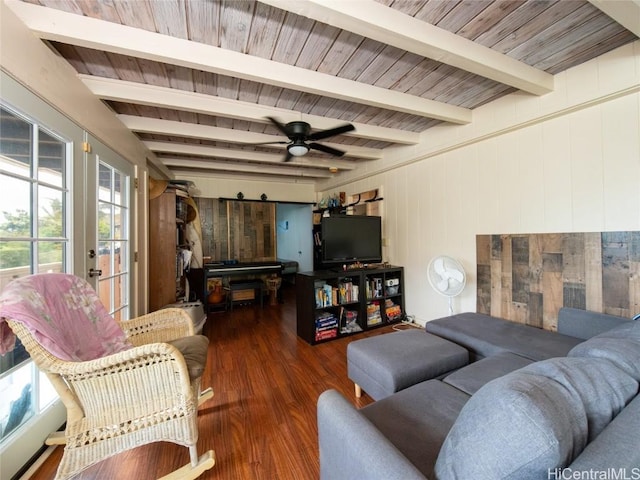 living room featuring dark hardwood / wood-style flooring, ceiling fan, wooden walls, a barn door, and beamed ceiling