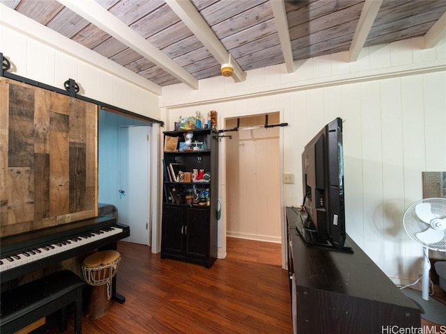 misc room featuring beam ceiling, a barn door, wood walls, and dark wood-type flooring