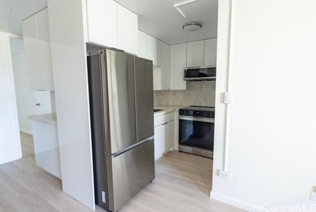 kitchen featuring white cabinets, appliances with stainless steel finishes, tasteful backsplash, and light hardwood / wood-style flooring