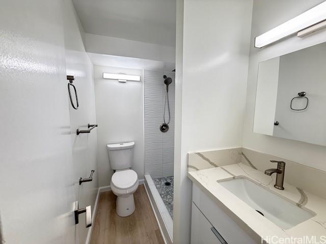 bathroom with hardwood / wood-style floors, vanity, toilet, and walk in shower