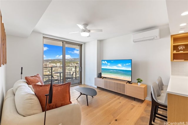 living room with ceiling fan, light hardwood / wood-style floors, and a wall mounted air conditioner