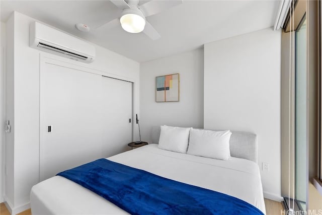 bedroom featuring a wall mounted air conditioner, ceiling fan, light wood-type flooring, and a closet