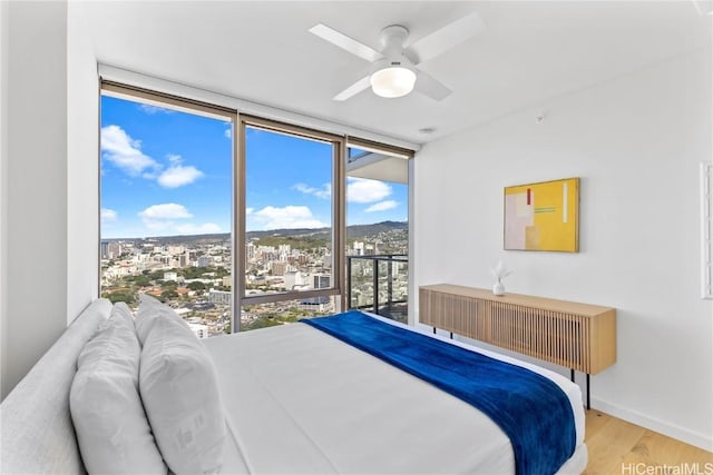 bedroom featuring ceiling fan, expansive windows, and light wood-type flooring