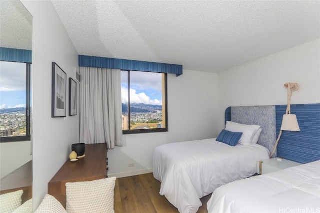 bedroom featuring dark hardwood / wood-style flooring, a textured ceiling, and multiple windows