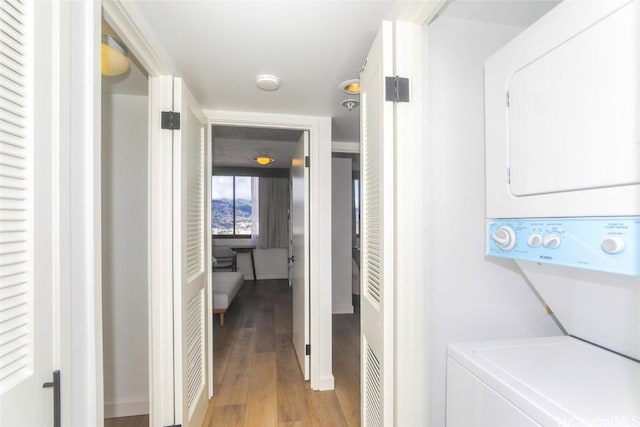 laundry area with stacked washing maching and dryer and hardwood / wood-style flooring