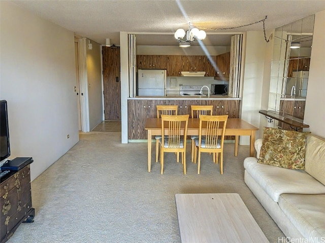 kitchen featuring kitchen peninsula, a textured ceiling, ventilation hood, white refrigerator, and a notable chandelier