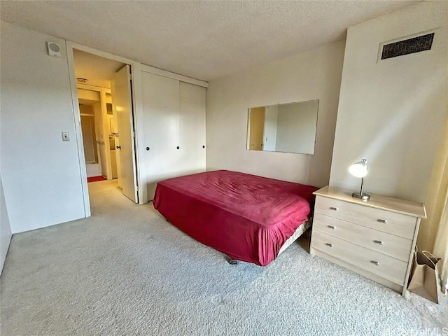 carpeted bedroom with a textured ceiling and a closet