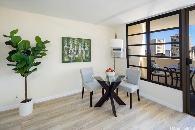 dining space featuring a wall mounted air conditioner and light hardwood / wood-style floors