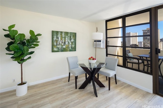 dining area featuring an AC wall unit and light hardwood / wood-style flooring