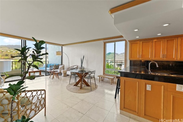 kitchen with light tile patterned floors, a sink, decorative backsplash, brown cabinets, and dark countertops