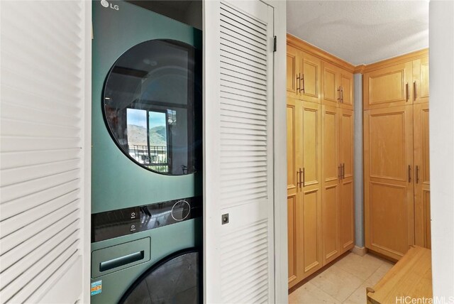 washroom with stacked washer / drying machine and light tile patterned flooring