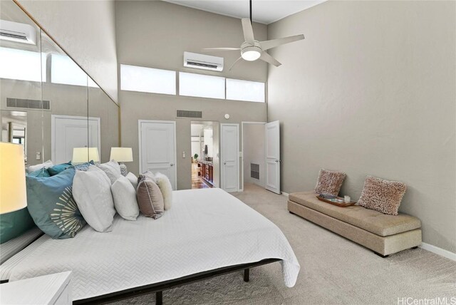 bedroom with ceiling fan, light colored carpet, a towering ceiling, and a wall unit AC