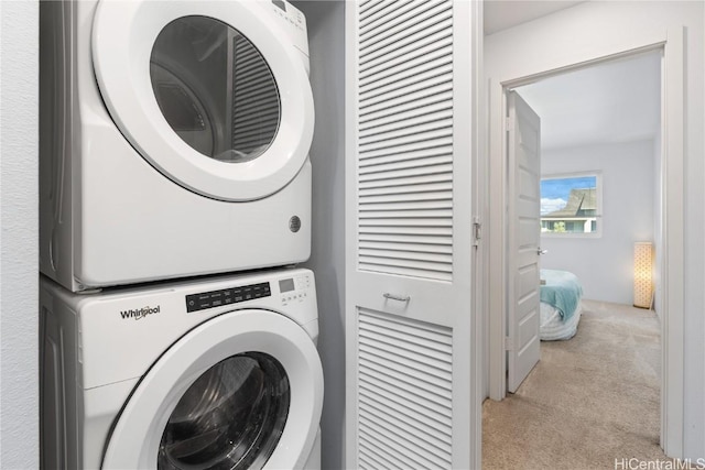 laundry area featuring stacked washer / drying machine and light carpet