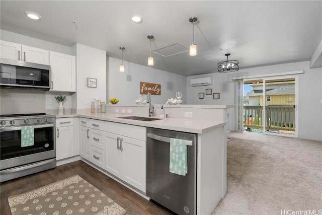 kitchen with appliances with stainless steel finishes, kitchen peninsula, sink, and hanging light fixtures