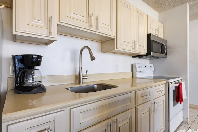 kitchen with a textured ceiling, sink, light tile patterned floors, cream cabinetry, and white electric range