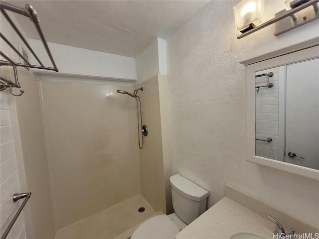 bathroom featuring toilet, vanity, and tiled shower