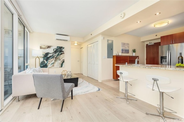 interior space with a wall mounted air conditioner, a breakfast bar, electric panel, stainless steel refrigerator with ice dispenser, and light hardwood / wood-style flooring