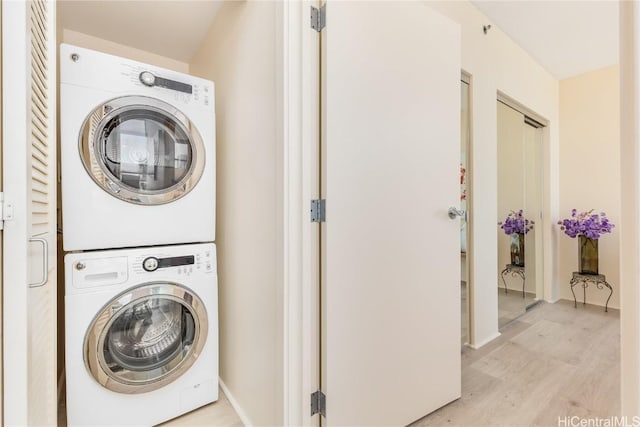 laundry area with stacked washer and dryer and light wood-type flooring