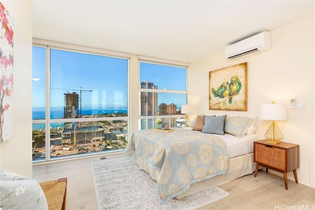 bedroom featuring a water view, floor to ceiling windows, a wall mounted AC, and wood-type flooring