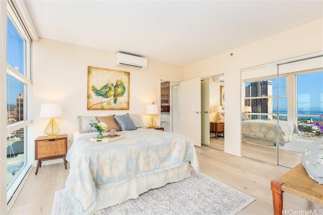 bedroom featuring multiple closets, a wall mounted air conditioner, and light hardwood / wood-style flooring