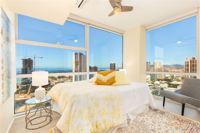 bedroom with expansive windows, ceiling fan, and hardwood / wood-style flooring